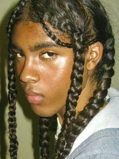 a close up of a person with long braids on her head and wearing a gray shirt