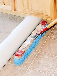 a mop is laying on the floor next to a broom and some cabinets in a kitchen