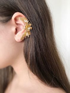 Gorgeous modern style ear cuff decorated with delicately shaped leaves. You can use our ear cuff on the right or left side.  Has a rode metal soldered on the back of it that could be  opened for an easy wear or squeezed inwards for a secure fit. The set includes a mini zirconium stud earring for the second ear VAT: Value Added Tax (VAT) is a tax that is charged when your parcel reaches the destination country. You may be required to pay VAT in order to receive your parcel. Customs policies and import duties vary widely from country to country, and we have no control over these charges. As a guide: USA: from 800 USD UK: 20% EU: 15% CUSTOM ORDERS If you liked the product, but you want to make your own changes, color / length / use of other beads. Please tell me about it in a personal message Adjustable Gold Ear Climbers For Gift, Elegant Gold Ear Climbers For Wedding, Dainty Ear Climbers For Party, Gold Single Ear Cuff As A Gift, Dainty Single Ear Cuff For Party, Dainty Ear Climbers For Parties, Adjustable Gold Cartilage Earrings For Party, Gold Ear Cuff For Party, Elegant Adjustable Gold Ear Cuff