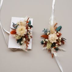 two boutonnieres with flowers and feathers on them sitting next to each other