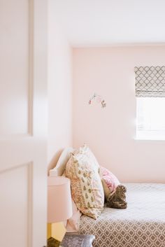 a bedroom with pink walls and pillows on the bed