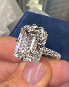 a close up of a person's hand holding an engagement ring with a large diamond in the center