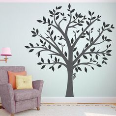 a living room with a chair and tree wall decal