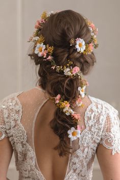 the back of a woman's head with flowers in her hair, wearing a wedding dress