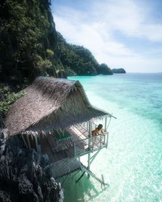 a small hut on the edge of an ocean with a dog in it's lap