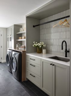 a washer and dryer sitting in a kitchen next to a counter with flowers on it