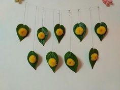 some yellow flowers and green leaves hanging on a string