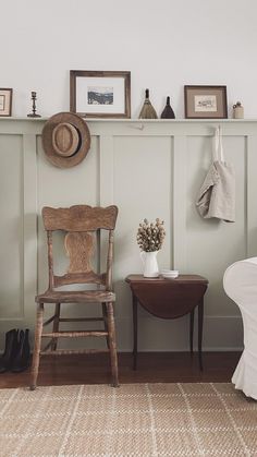 a living room with a chair, table and pictures on the wall above it's headboard