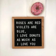 a pink donut sitting on top of a wooden sign that says roses are red violets are blue i love donuts as much as i love you