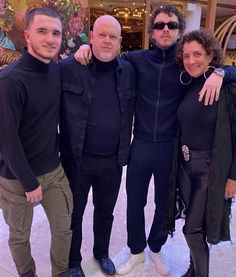 four people posing for a photo in front of a building with christmas decorations on the walls