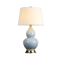 a light blue lamp with a white shade on the base and a gold metal base