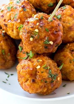 a white plate topped with meatballs covered in sauce and garnished with parsley