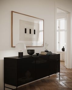 an empty room with a black cabinet and white painting on the wall next to it