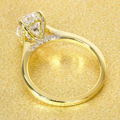 a yellow gold ring with two diamonds on the top and bottom, sitting on a shiny surface