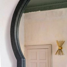 a mirror that is hanging on the wall next to a door with a vase in front of it