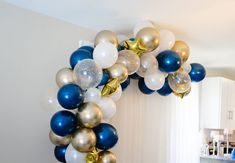 the balloon arch is decorated with blue, gold and white balloons