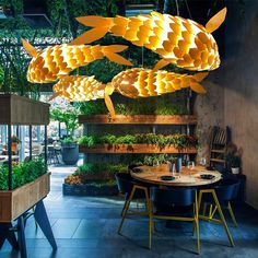 an indoor restaurant with plants hanging from the ceiling and wooden tables in front of it