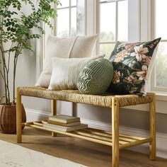 a wooden bench with pillows on it next to a window and a potted plant