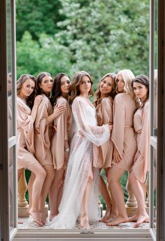 the bridesmaids are all dressed in nude colored robes and posing for a photo