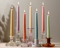 there are many different colored candles next to each other on the table with one candle in between them