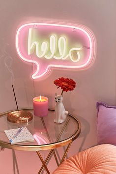 a neon sign that says hello on the side of a table next to a vase with flowers