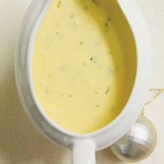 a white bowl filled with soup sitting on top of a counter next to a spoon