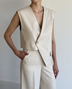 Midweight woven fabric. Boxy fit . Notch lapels. Sleeveless Asymmetric hem. Front flap pockets. Single front button closure  Lined 86% Polyester 12% Linen 2% Elastane ONE SIZE  Shoulder 15cm / 5.9in Bust 108cm / 42.5in Length 63cm / 24.8in Sleeveless Summer Vest For Tailoring, Chic Vest With Pockets, Tailored Beige Vest For Business Casual, Sleeveless Beige Outerwear For Work, Chic Asymmetrical Vest For Spring, Beige Notch Lapel Vest For Spring, Beige Vest For Work, Chic Asymmetrical Vest For Work, Beige Sleeveless Outerwear For Work