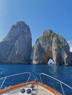 the bow of a boat with an arch in the water and two large rocks behind it