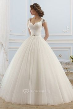 a woman in a white wedding dress standing on a wooden floor next to a window