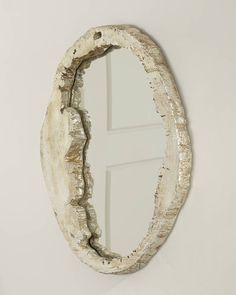 an oval mirror hanging on the wall next to a white wall with a wooden frame