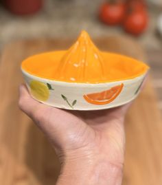 a person is holding a small bowl with an orange design on it and a plastic funnel