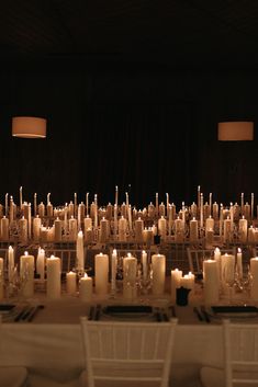 rows of lit candles sit in front of white chairs