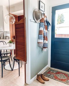 a blue front door with a hat and scarf hanging on the wall next to a pair of shoes