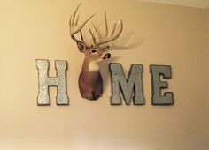 a deer head mounted to the side of a wall next to letters that spell home