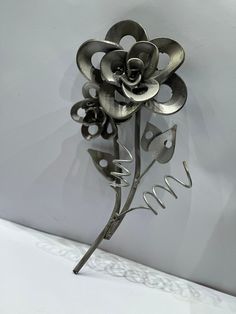 a metal flower on a white surface with the word love spelled below it and an image of a rose