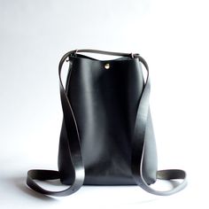 This convertible backpack, the Crossback 3-in-1 Bag, is as beautiful as is practical! Convert from shoulder or crossbody to a backpack with this one bag!Black LeatherBlack Leather StrapsBrass Hardware ... • Fast & FREE Shipping on orders over $150• Made with a single piece of Full-Grain leather• Snap button closure• Button studs on each side to add support as a crossbody bag• Top extender• Open interior pocket• Measurements: 14" wide across top, 11” wide across bottom, 15" high, 5" deep• Handle Modern Leather Bucket Backpack With Adjustable Strap, Modern Everyday Leather Bucket Backpack, Modern Bucket Bag Backpack With Adjustable Strap, Modern Bucket Bag Backpack With Detachable Strap, Minimalist Bucket Bag With Detachable Handle For Travel, Modern Bucket Backpack For Daily Use, Versatile Crossbody Backpack, Modern Crossbody Backpack With Leather Handles, Modern Crossbody Leather Backpack For Errands