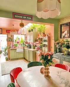 a kitchen filled with lots of green and pink furniture next to a dining room table