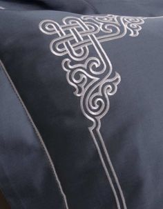 an embroidered pillow with a decorative design on the front and back side, in grey