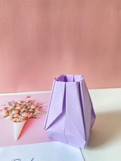 an origami vase sitting on top of a table next to a greeting card