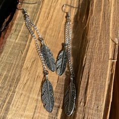 Silver feather charm earrings. Each shoulder-grazing dangle earring features two silver double-sided feather charms hung from different lengths of silver chain.  All Smallest Planet jewelry is handmade and handsomely packaged for easy gifting. * Ear wires and other earring findings can be swapped out for leverbacks or clip-ons--or for different metals or colors--on request. Bohemian Nickel-free Long Drop Earrings, Adjustable Silver Earrings With Feathers, Adjustable Dangle Feather Jewelry, Bohemian Nickel-free Long Drop Chandelier Earrings, Adjustable Silver Feather Earrings, Silver Bohemian Feather Earrings, Planet Jewelry, Bohemian Silver Feather Earrings, Earrings Funky