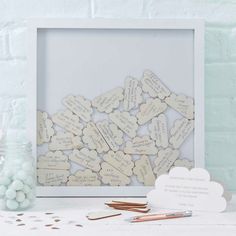 a white frame filled with lots of wooden hearts next to some pens and pencils