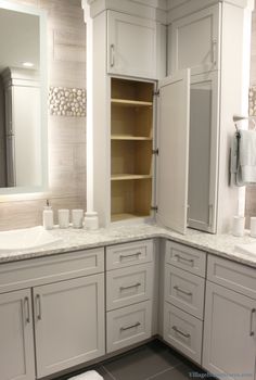 a bathroom with white cabinets and marble counter tops