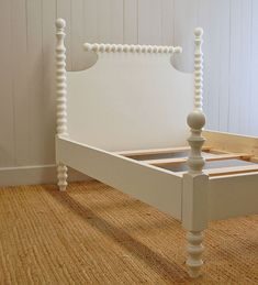 a white bed frame sitting on top of a carpeted floor next to a wall