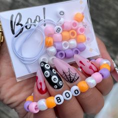 a person holding some fake nails and bracelets with beads on them that spell out boo