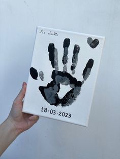 a handprint is held up in front of a white wall with black and gray prints