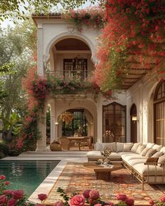 an outdoor living area with couches, tables and flowers on the ground near a pool