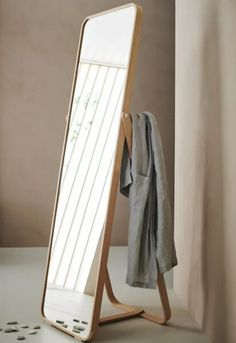 a mirror with clothes hanging on it next to a coat rack