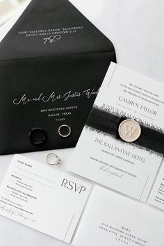 the wedding stationery is laid out on top of the black and white envelopes