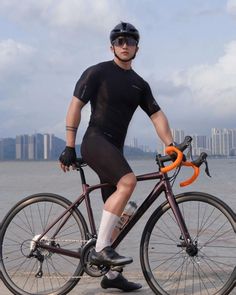 a man is posing with his bike by the water