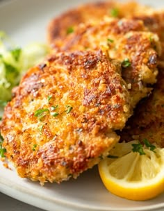 two crab cakes on a plate with lemon wedges